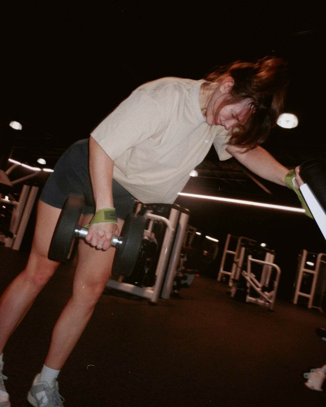 woman doing single arm exercise wearing uppper lifting straps